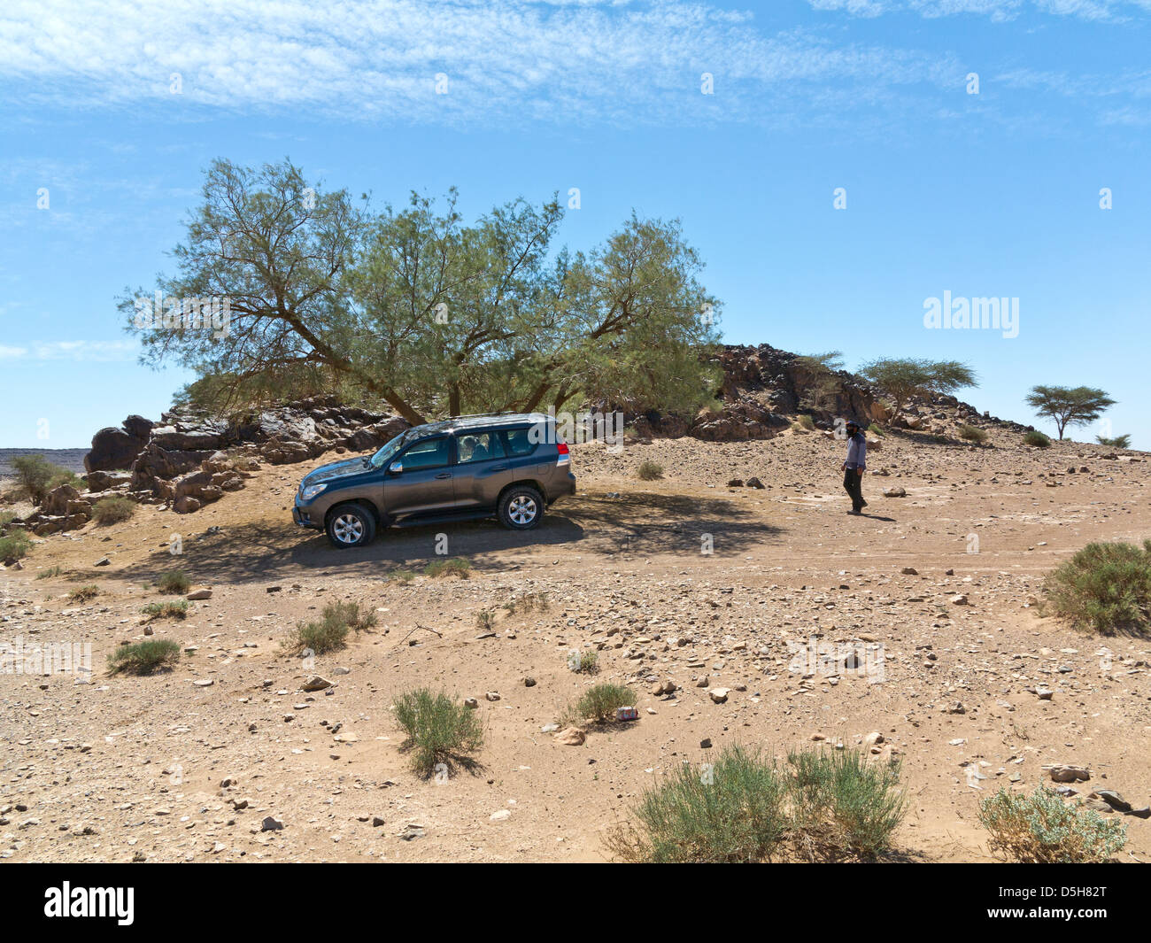 Voiture garée à la crête par des gravures rupestres préhistoriques à Oued Mestakou sur le Tata à Akka road au Maroc. Banque D'Images