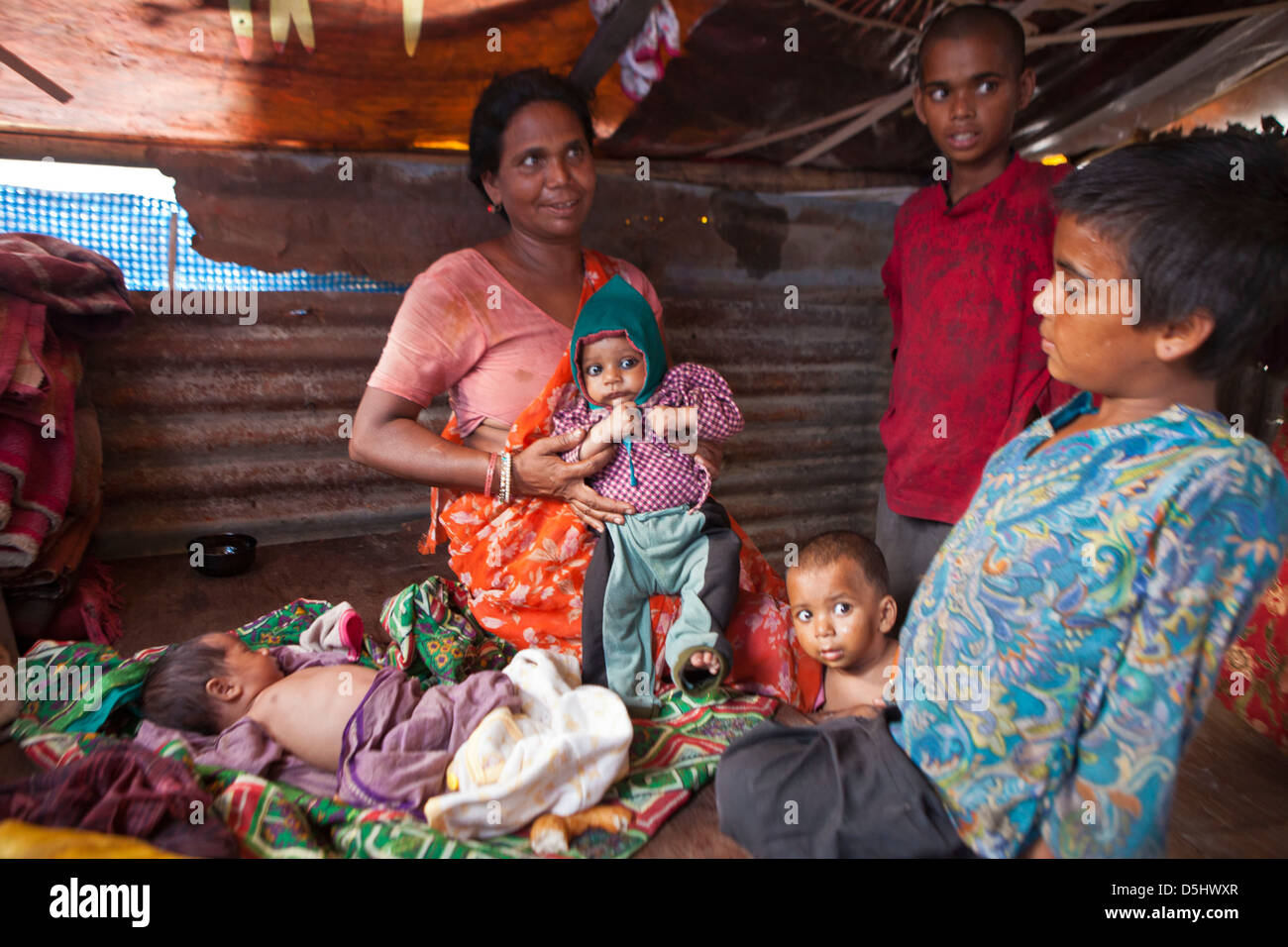 Moth népalais est titulaire d'un de ses enfants dans sa maison, dans la favela de Kankeshori domaine de Katmandou, Népal. Banque D'Images