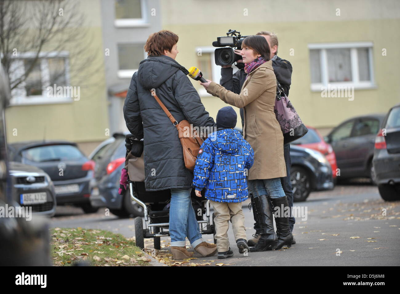 Les représentants des médias interview une mère en face de Daycare Centre 'Spatzennest' Altenburg, Allemagne, 16 novembre 2012. Centre de soins de jour à destination des travailleurs au moins trois enfants pour qu'ils ont leur sommeil de midi. Ces trois femmes où imeediately licenciés pour mettre en danger le bien-être des enfants. Photo : MARTIN SCHUTT Banque D'Images