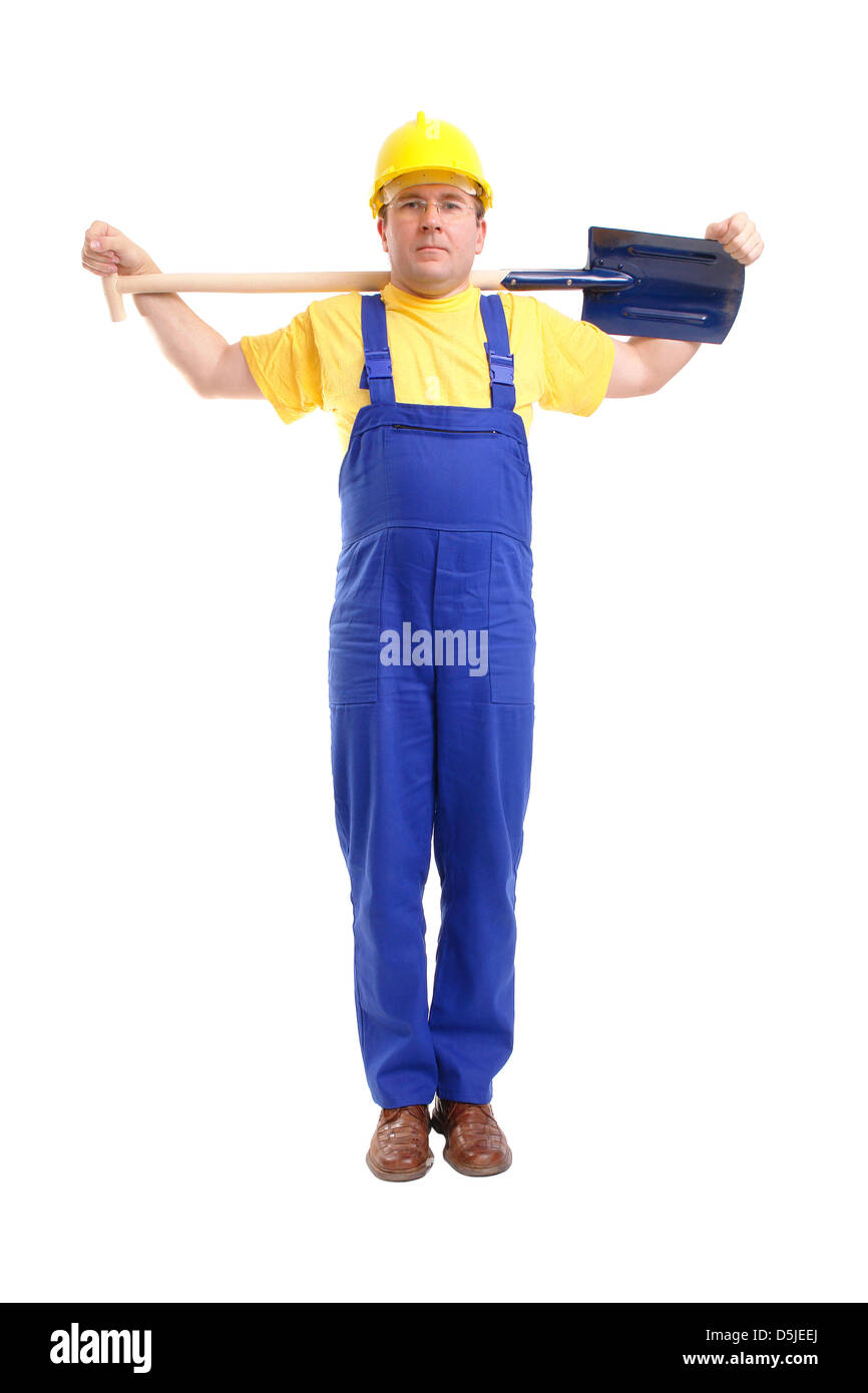Construction Worker wearing casque jaune et bleu dans l'ensemble posant avec pelle mis sur les épaules sur fond blanc Banque D'Images