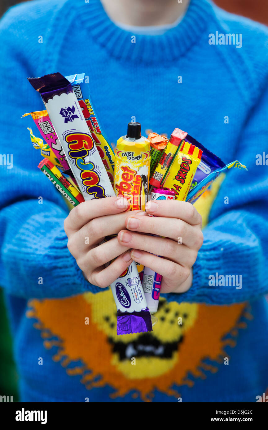 Les garçons mains tenant un assortiment de bonbons et sucreries rétro pour enfants Banque D'Images