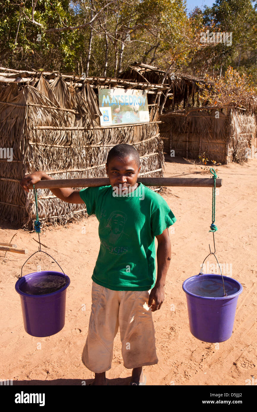 Madagascar, l'exploitation, Matsedroy Wallacea forest camp, homme de la région travaillant comme porteur d'eau avec des seaux d'eau sur les épaules Banque D'Images