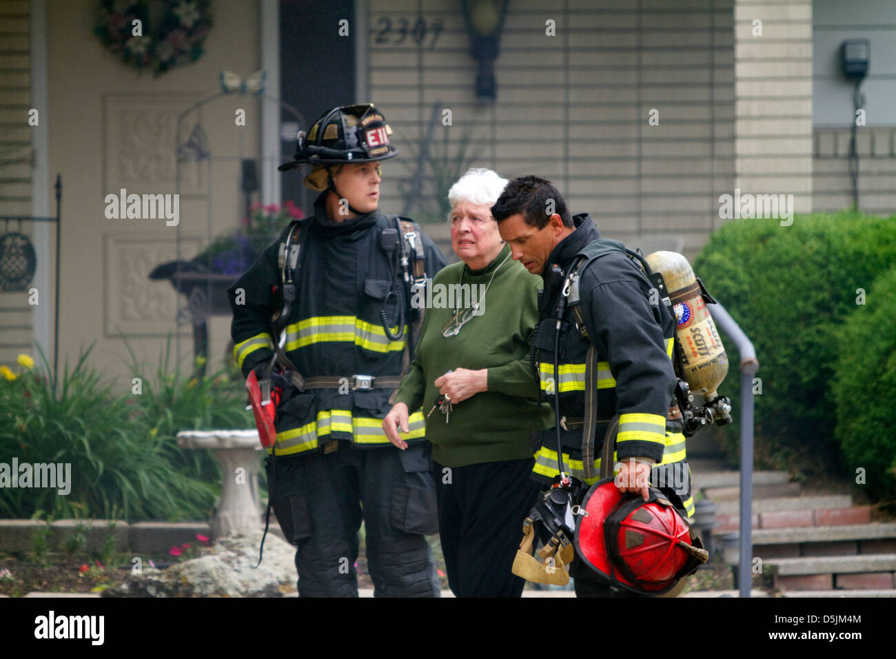 Les pompiers d'aider un résident au cours d'une maison en feu à Boise, Idaho, USA. Banque D'Images