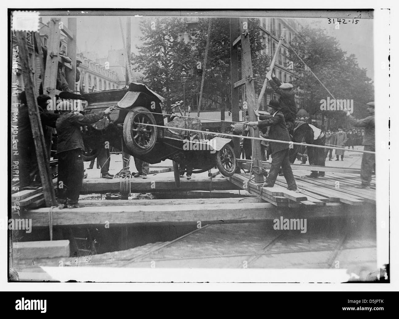 Une photographie prise en 1914 montre un taxi émergeant d'un grand trou dans la rue de Paris, France. L'image capture un moment inhabituel de la vie urbaine à une époque de défis infrastructurels. Banque D'Images