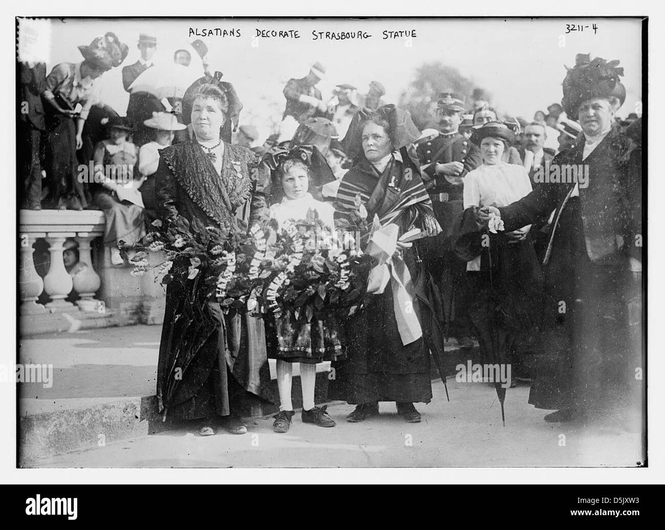 À Strasbourg, les Alsaciens décorent une statue dans le cadre d’une cérémonie, avec des costumes traditionnels, des couronnes et des fleurs, mettant en valeur les pratiques culturelles et les célébrations régionales. Banque D'Images
