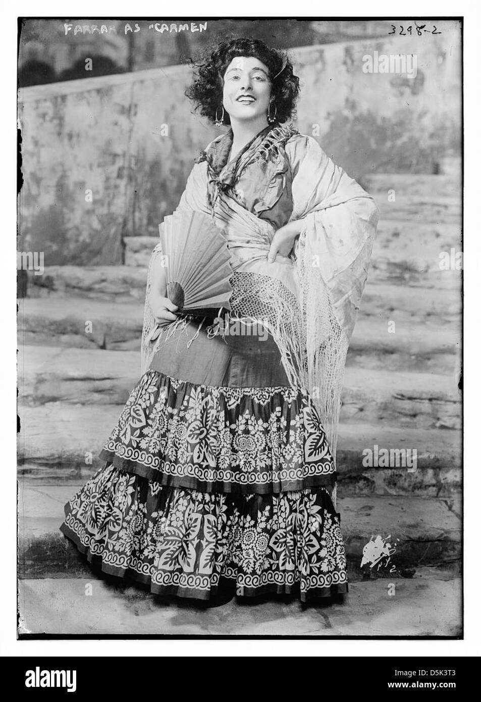 L'actrice Geraldine Farrar incarne le personnage de Carmen dans un opéra. L'image montre Farrar en costume avec des cheveux bouclés, un éventail, des boucles d'oreilles et un châle, incarnant le rôle passionné et dramatique qu'elle a joué sur scène. Banque D'Images