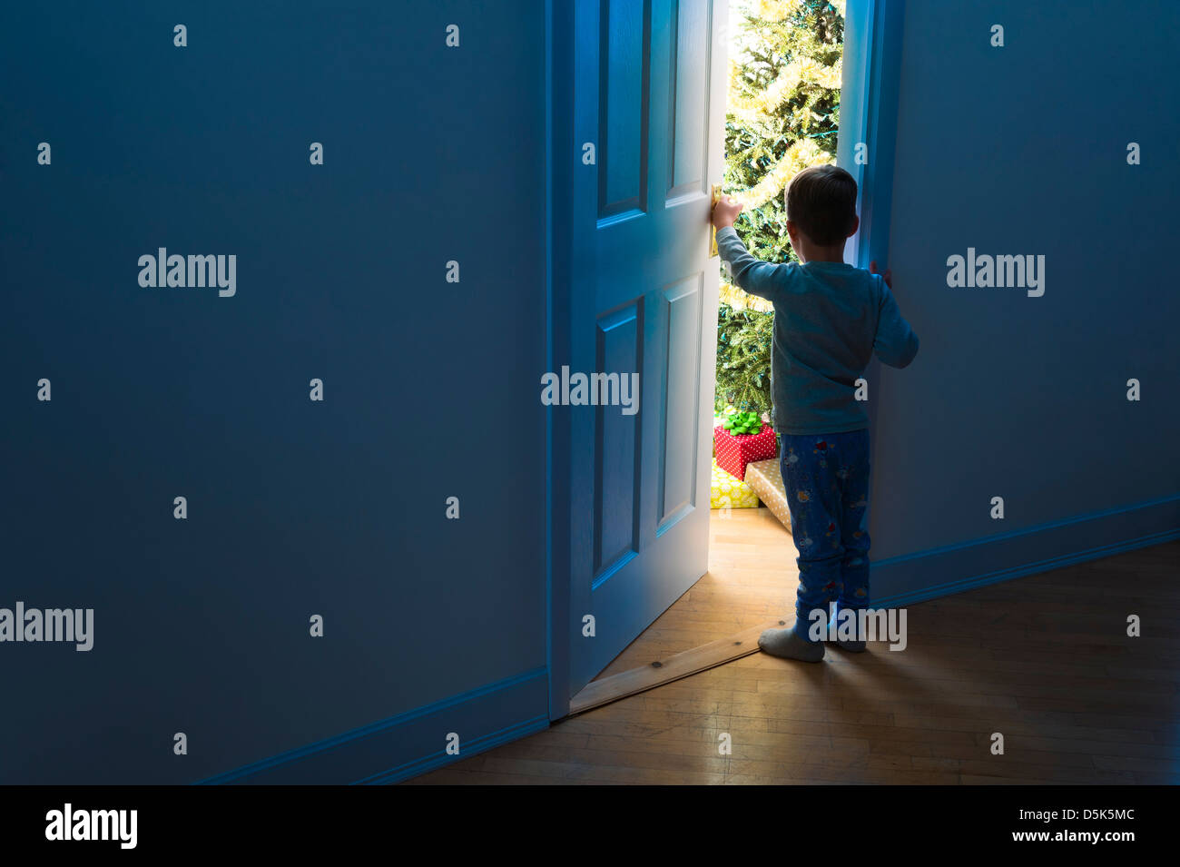 Boy (4-5) peeking through doorway Banque D'Images