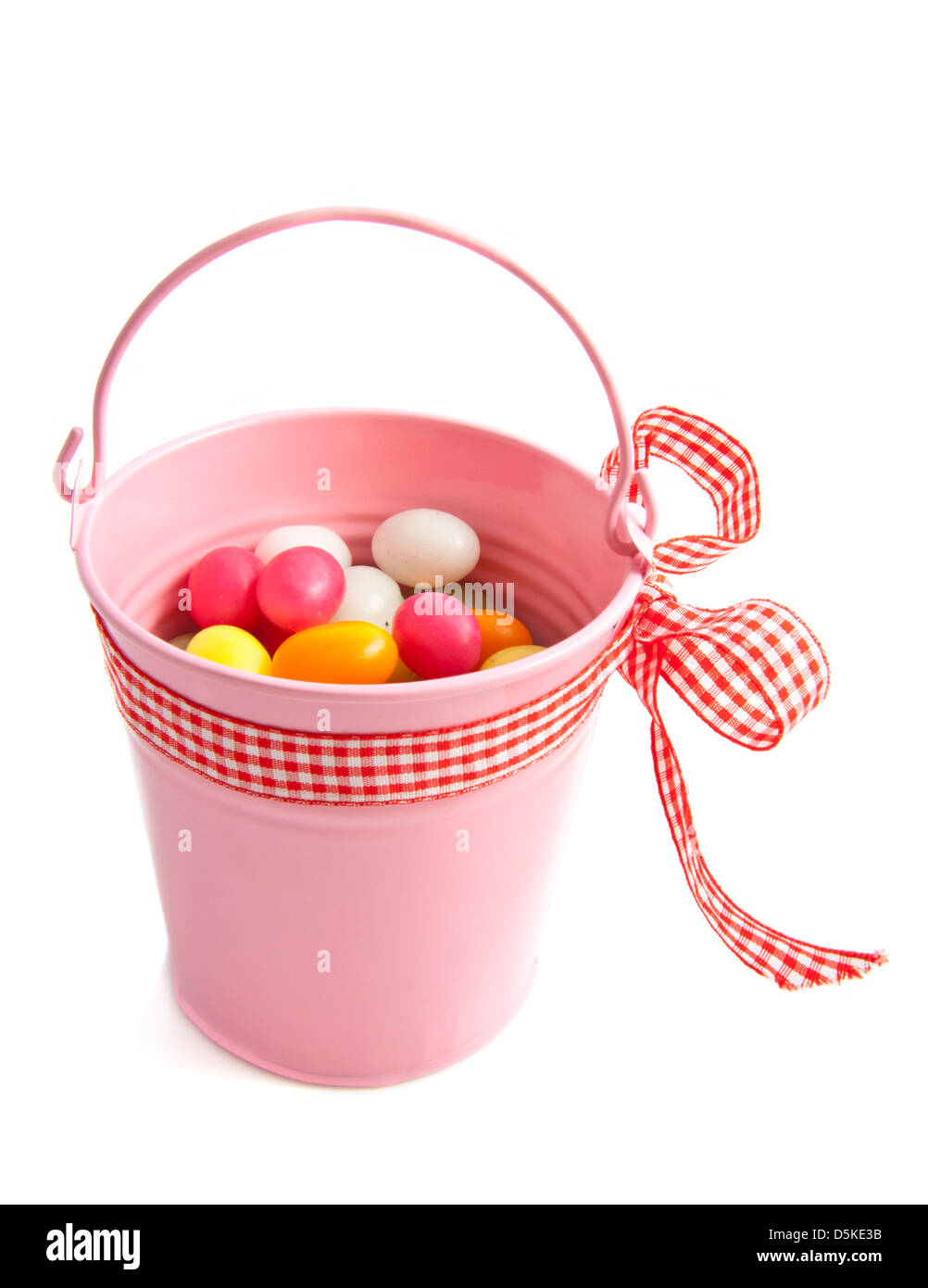 Pink bucket avec oeufs bonbons colorés sur fond blanc Banque D'Images