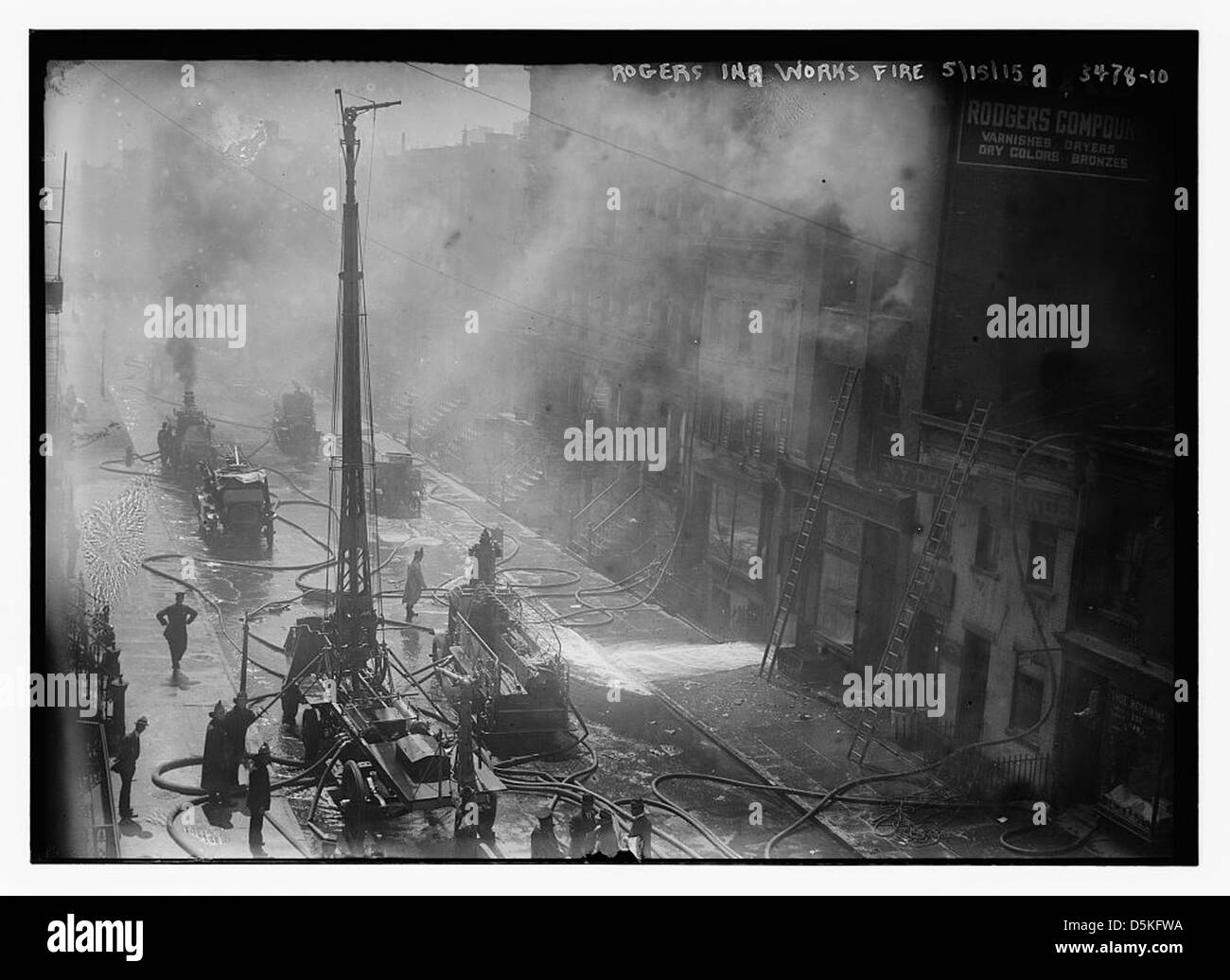 Cette image montre l'incendie à Rogers Ink Works à New York le 15 mai 1915. Les pompiers combattent l'incendie près de la voie ferrée surélevée, avec des canons à eau et des tuyaux utilisés pour contrôler le feu. Banque D'Images