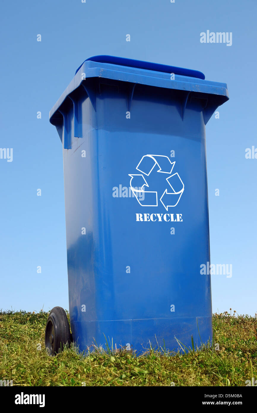 L'élimination en plastique bleu avec blanc réutilisent le casier dans l'herbe plus de ciel bleu Banque D'Images