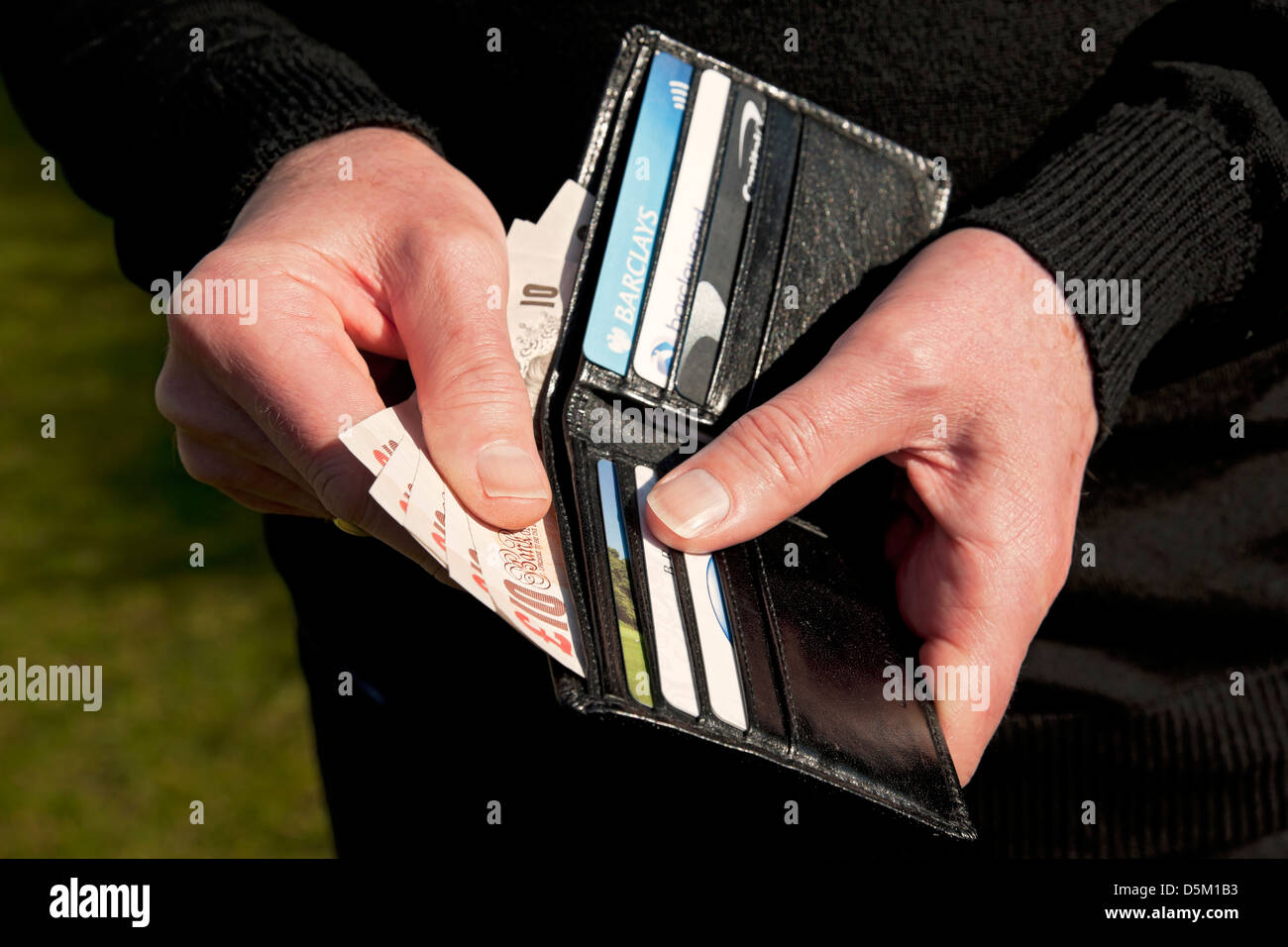 Gros plan de la main de personne homme tenant le portefeuille et dix livres livres sterling billets de 10 £ payant l'argent anglais British Cash Bank cartes de crédit Angleterre Royaume-Uni Grande-Bretagne Banque D'Images