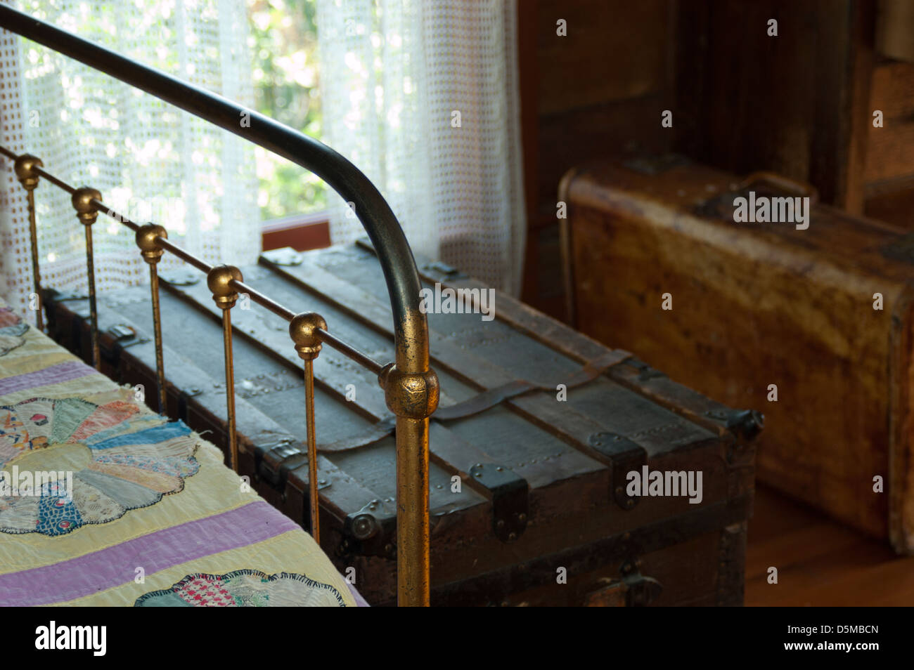 Chambre d'intérieur dans une ferme historique la maison, avec un lit en laiton antique, courtepointe, tronc de voyage et valise. Banque D'Images