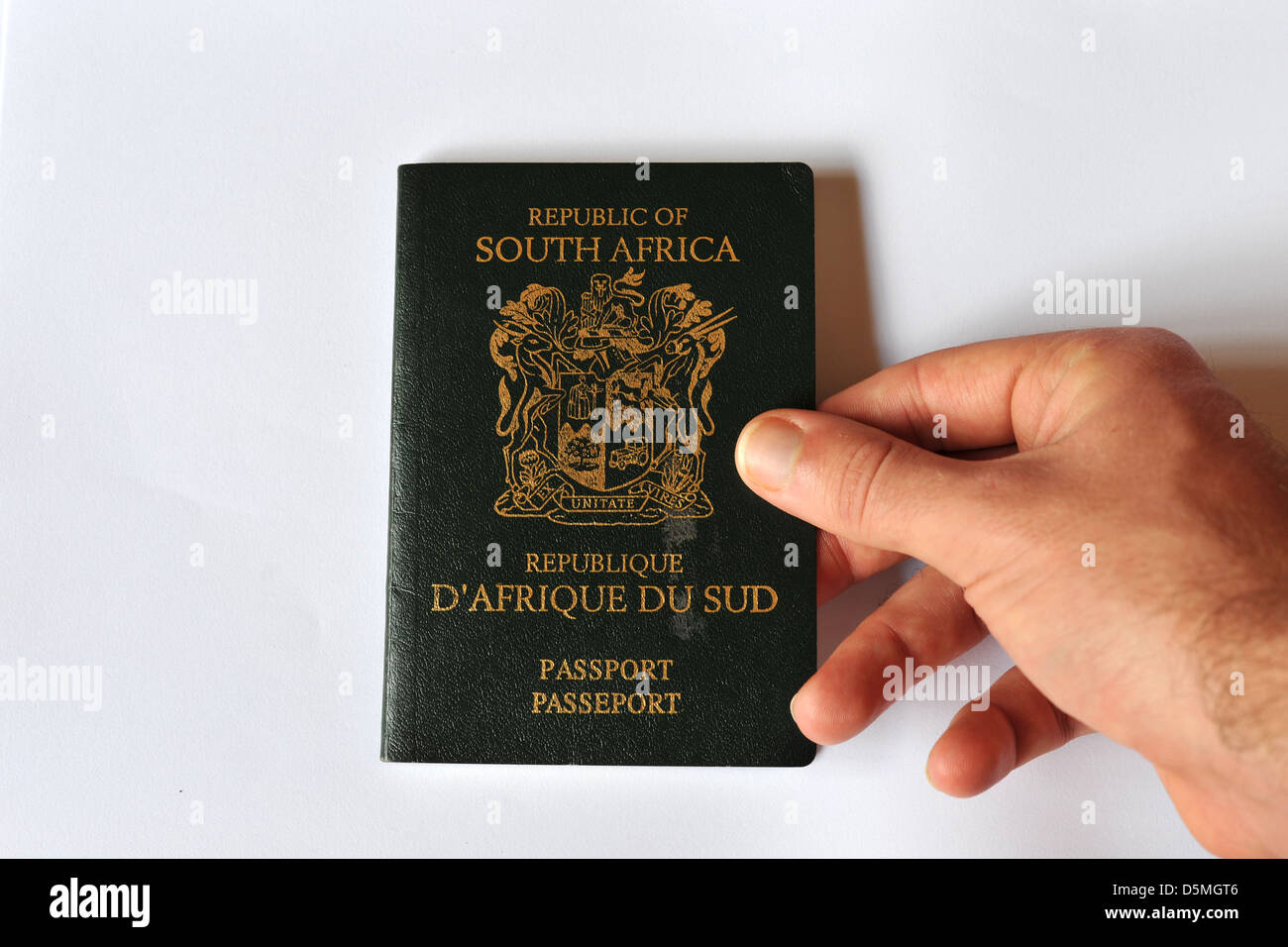 Une main blanche touchant l'ancienne conception de la passeport sud-africain en studio. Banque D'Images