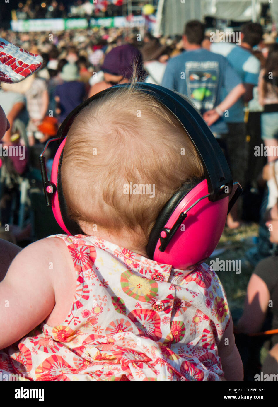 Un bébé portant un protège-oreilles au festival de Glastonbury Banque D'Images