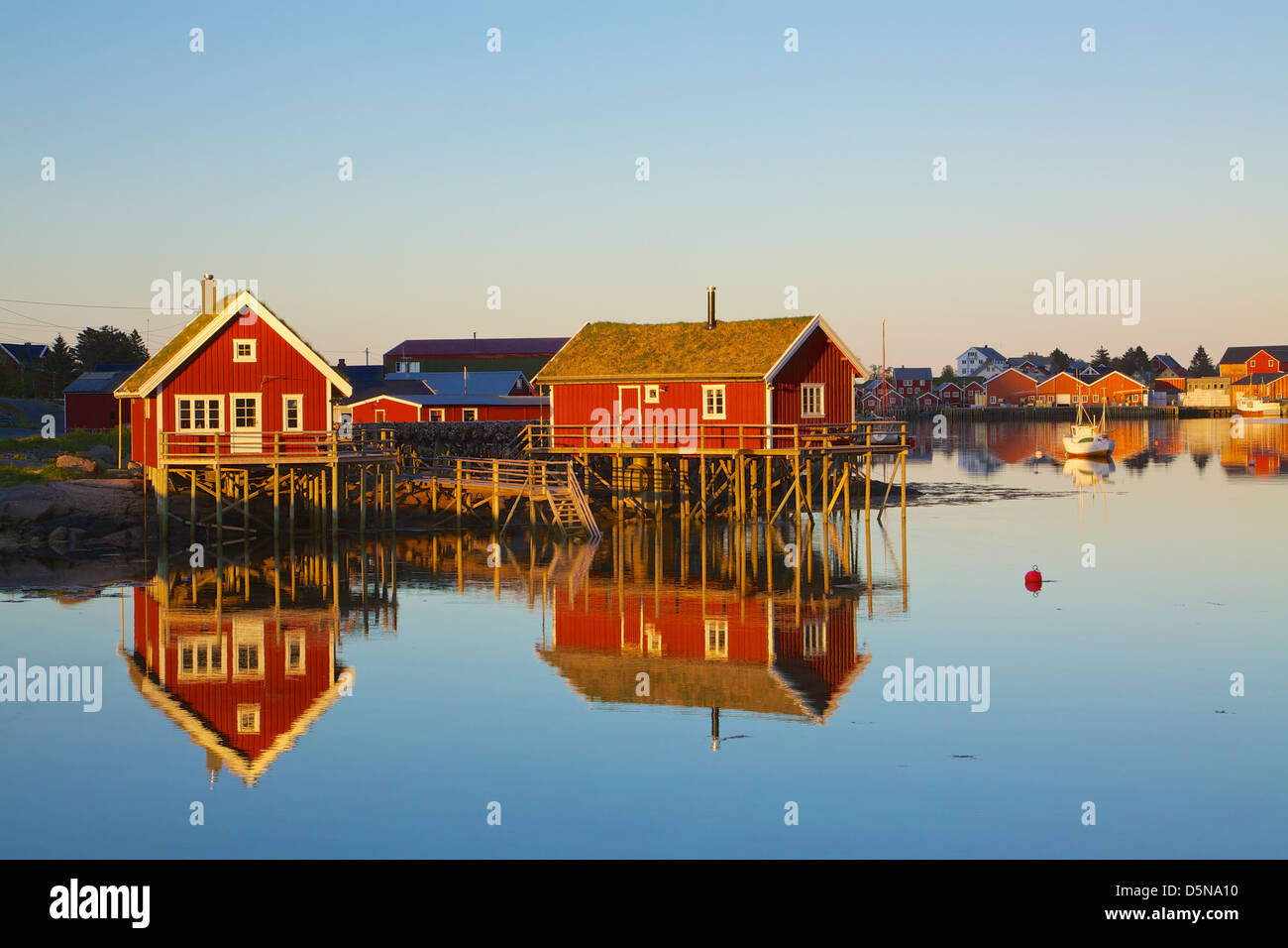 Rorbu rouges typiques huttes avec toit de chaume en ville de reine sur les îles Lofoten en Norvège éclairées par le soleil de minuit Banque D'Images