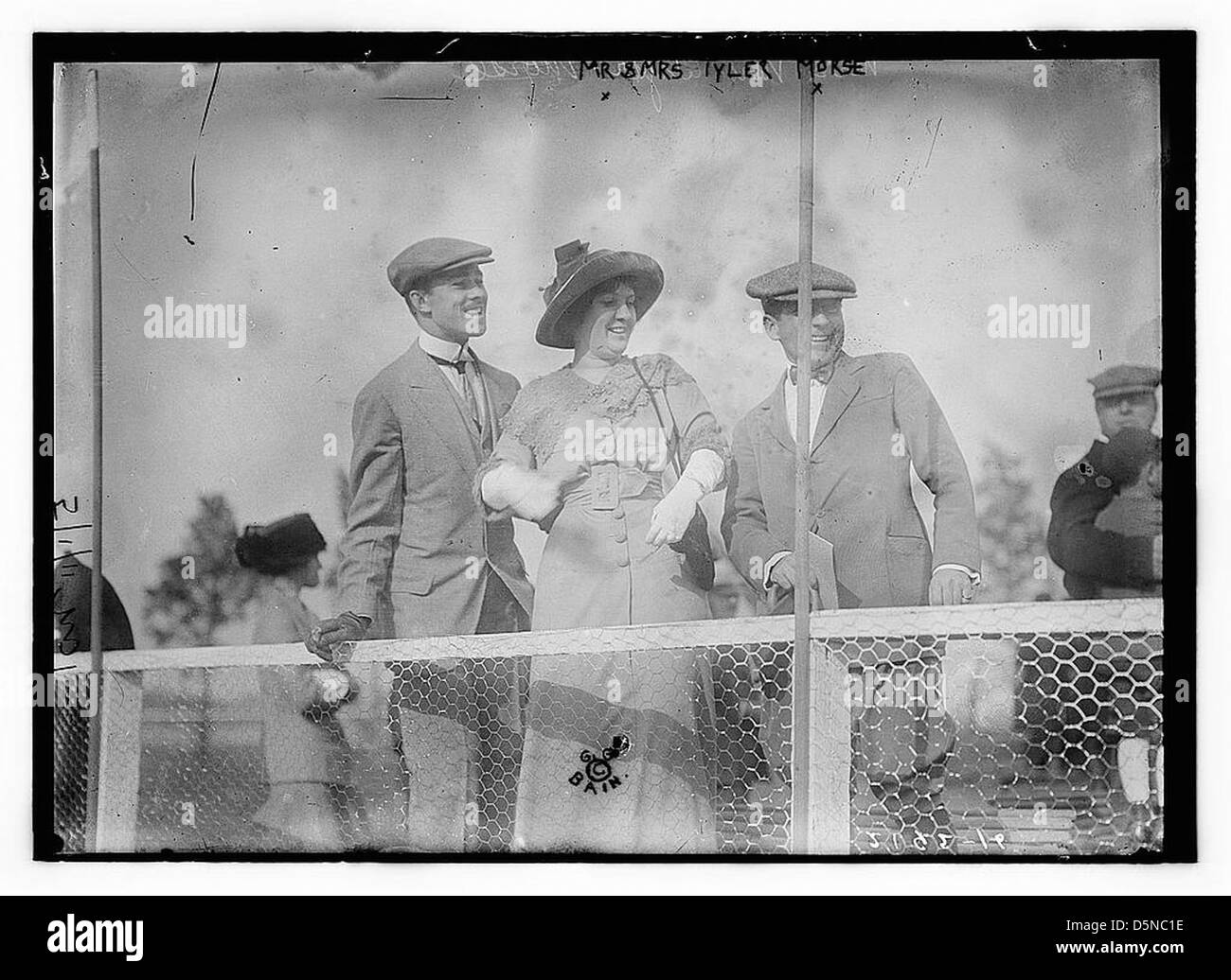 Une photographie de Mr. et Mrs. Tyler Morse à Belmont Park lors d'un événement du 1er mai dans les années 1910 Le couple est vu dans une tenue à la mode, avec la femme dans une robe, des gants et un chapeau, tandis que l'homme porte un costume. La scène se déroule sur une piste de course hippique avec des spectateurs en arrière-plan. Banque D'Images