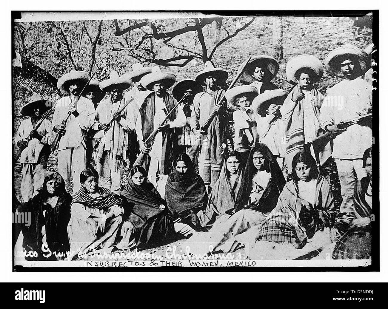 Cette photographie capture des révolutionnaires mexicains, connus sous le nom d'« Insurrectos », aux côtés de femmes, souvent appelées « Adelitas ». Armés de fusils, ils sont photographiés pendant la Révolution mexicaine au début du XXe siècle. Banque D'Images