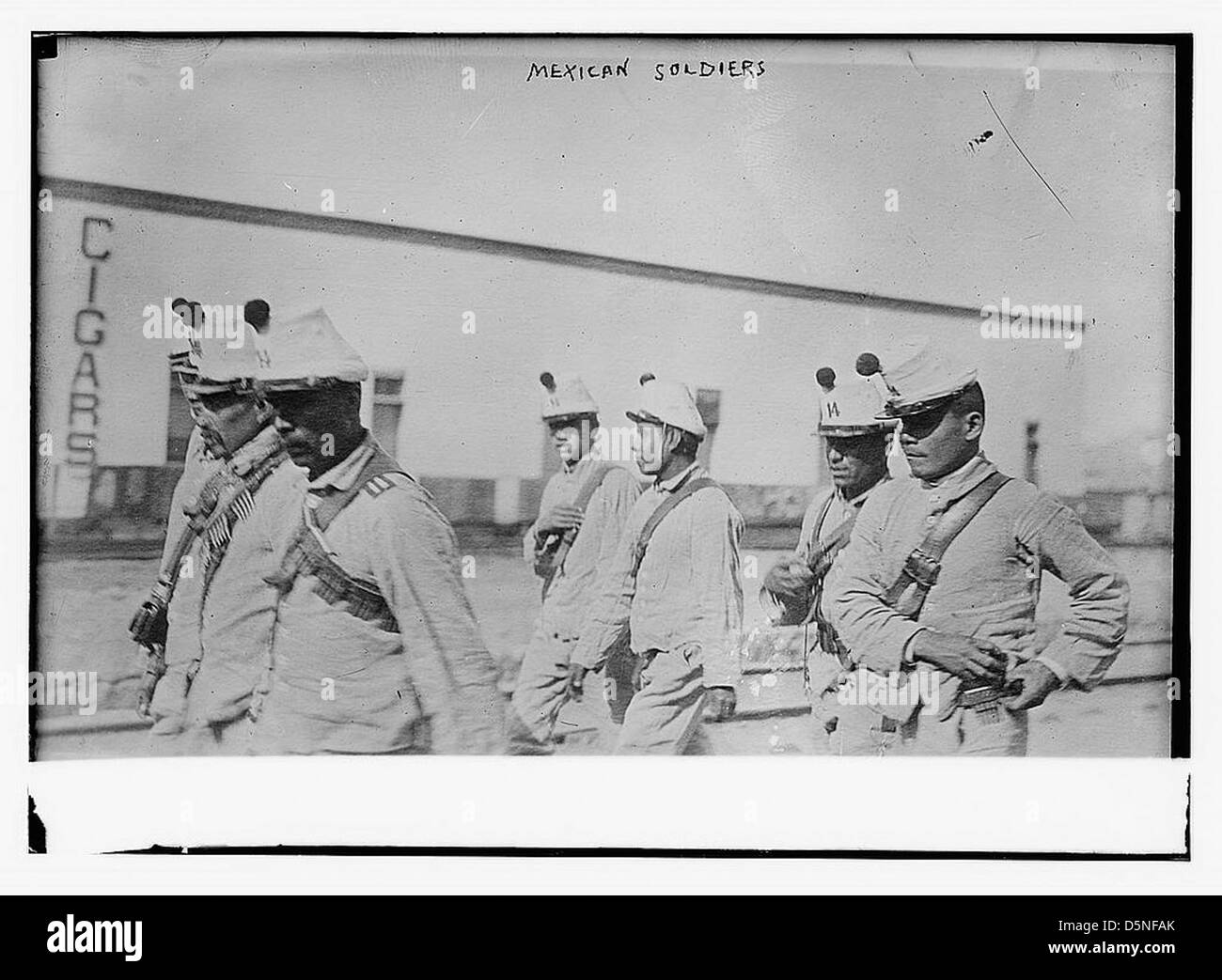 Cette photographie capture les troupes fédérales mexicaines au cours des années 1910, probablement au milieu de la Révolution mexicaine. Les soldats sont vus marcher en formation, certains portant des bandoliers et portant des munitions, mettant en valeur leur tenue militaire et l'atmosphère de la révolution. Banque D'Images