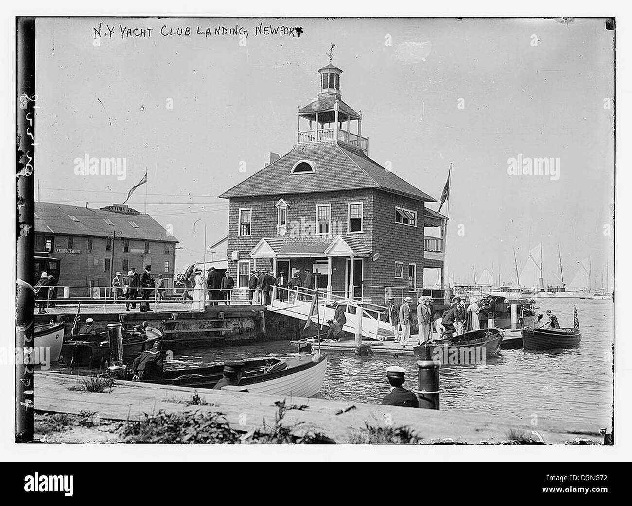 Cette photographie montre le débarquement du New York Yacht Club à Newport, Rhode Island, avec des bateaux amarrés au quai. Il capture l'élégance de l'emplacement du club au bord de l'eau et les activités maritimes de la région. Banque D'Images