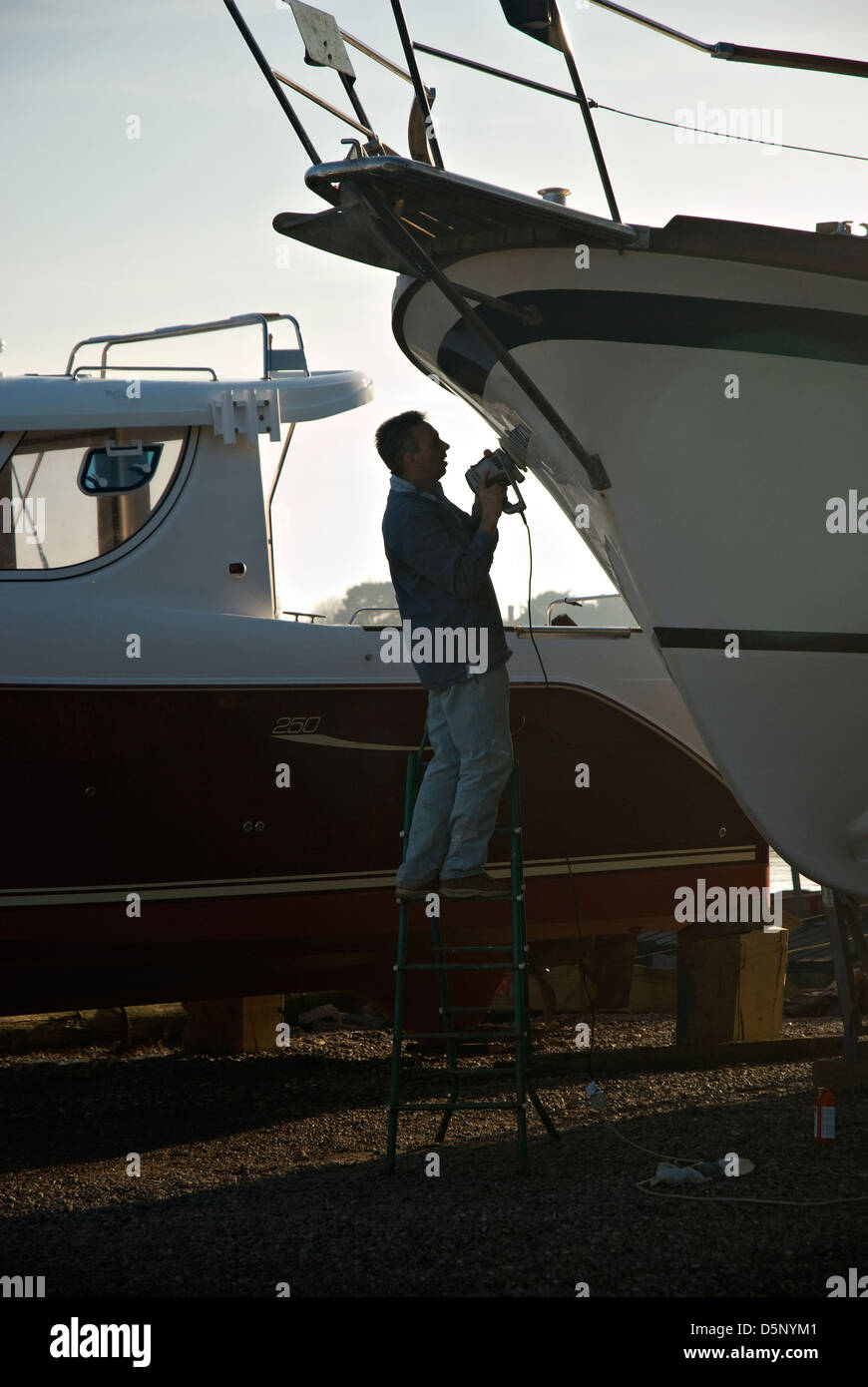 Une silhouette semi mâle effectuer les réparations sur son bateau. Banque D'Images