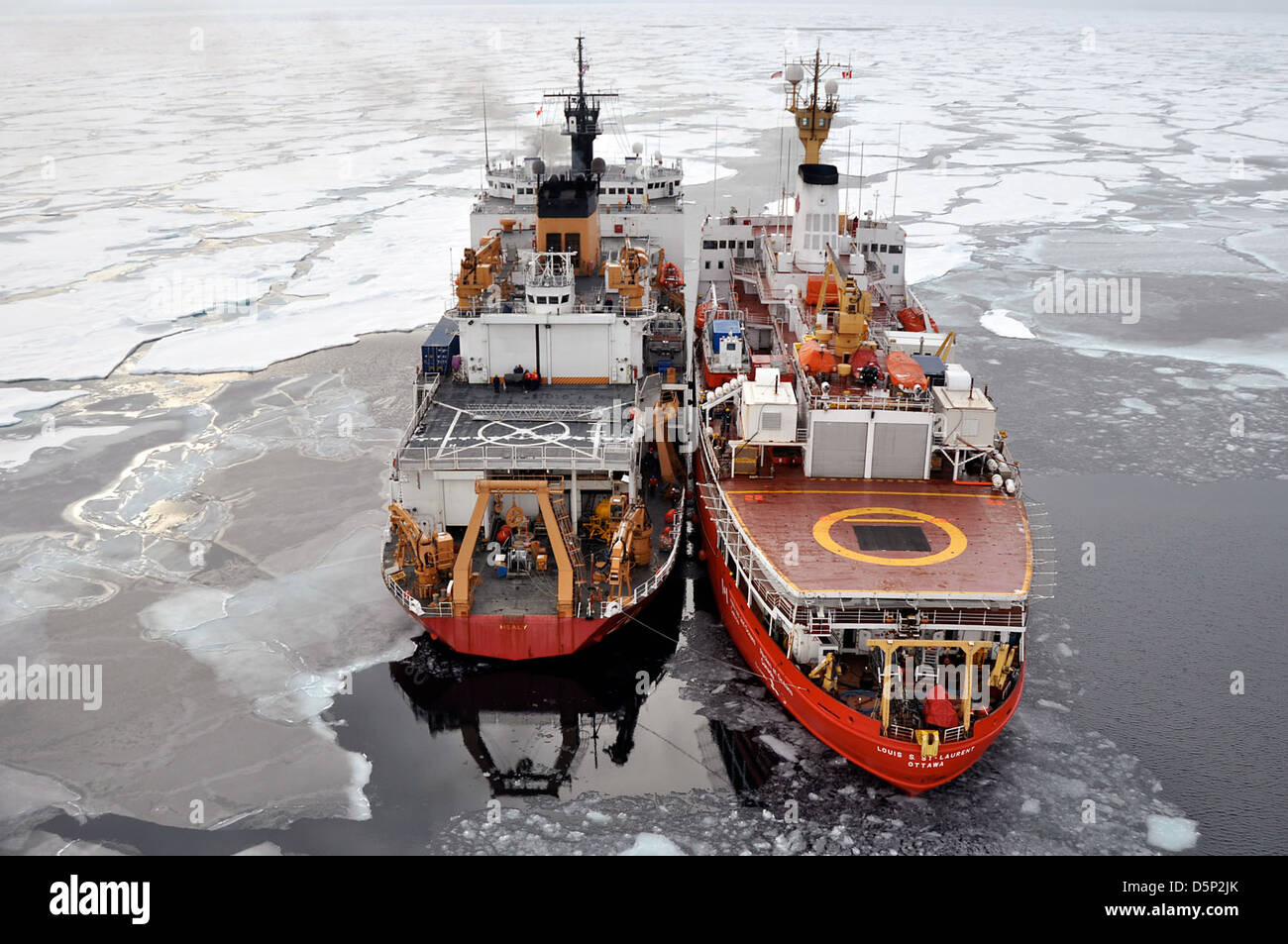 Cette image représente le canot *Salish côtier*, mettant l'accent sur la qualité de l'eau, avec un couteau *USCG St-Laurent* dans l'Arctique. Il met en valeur le rôle de la Garde côtière dans les opérations dans l'Arctique et la surveillance de la glace de mer. Banque D'Images