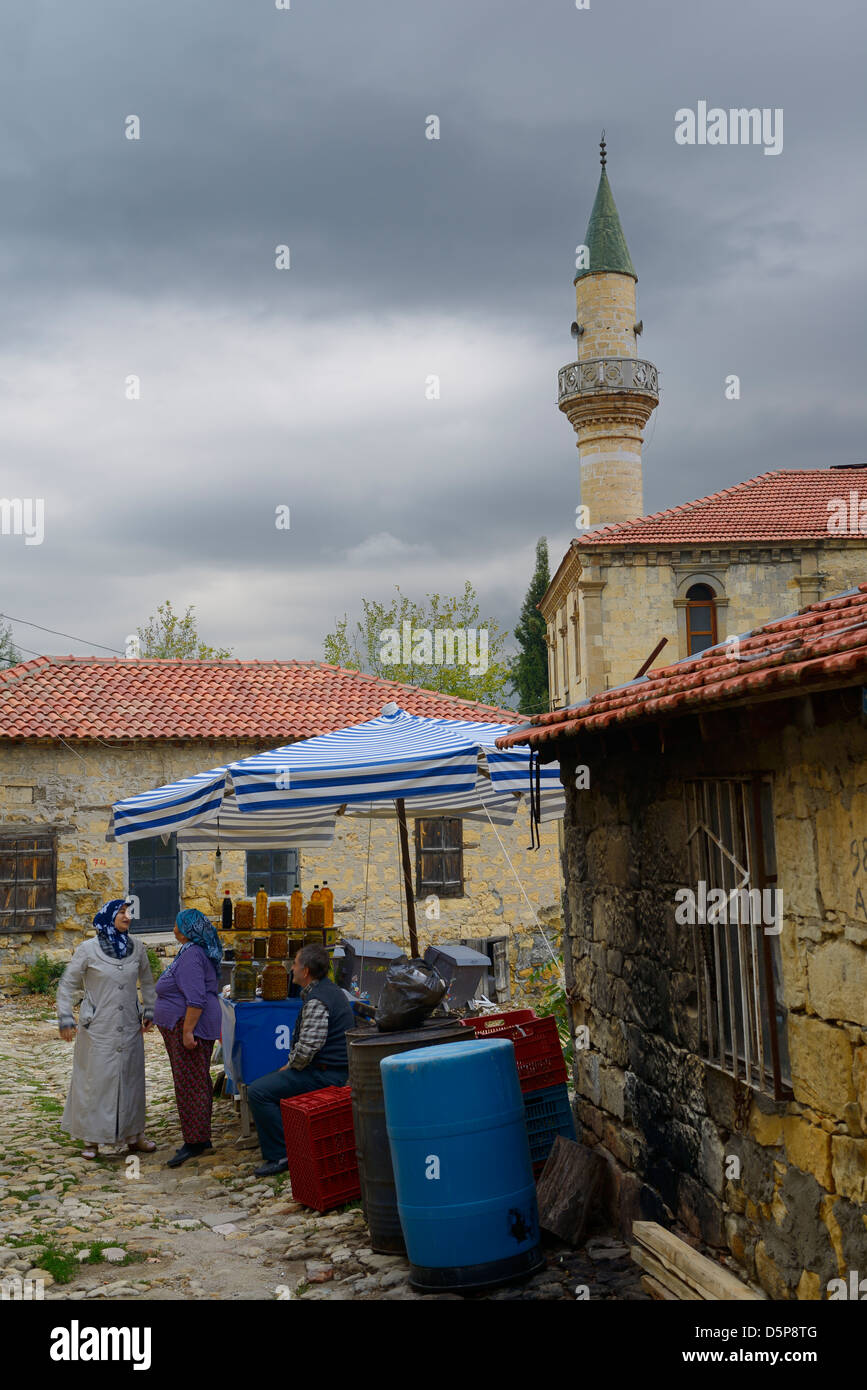 Les femmes locales à parler à un stand d'olive dans l'ancien village sur une colline de yesilyurt turquie avec minaret Banque D'Images