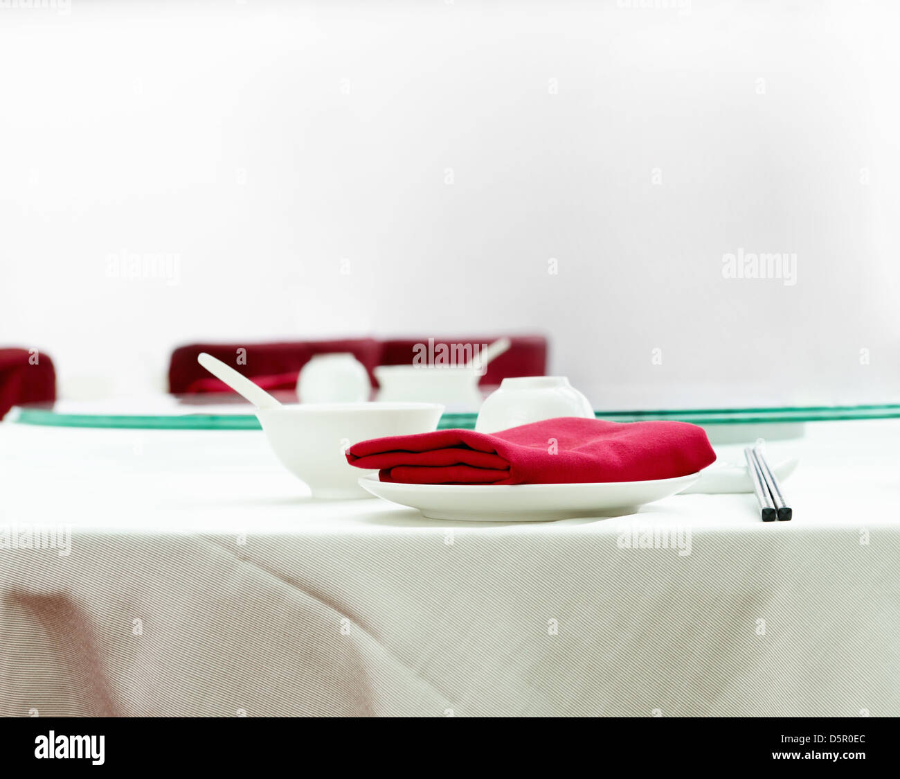 Réglage de la table sur un élégant, blanc table à manger dans un restaurant chinois avec des serviettes de table rouge Banque D'Images