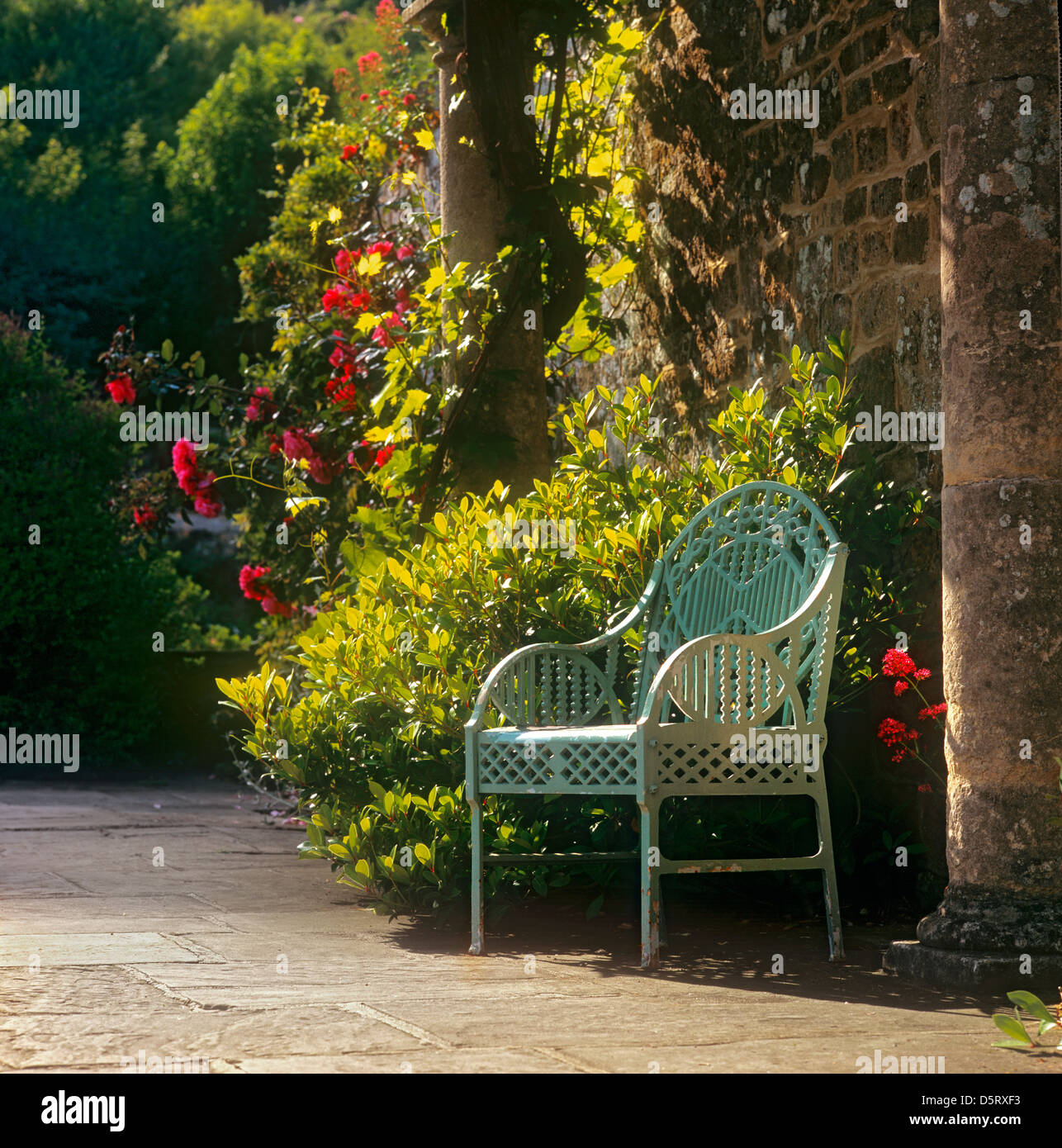 Treillis classique chaise de jardin en métal, sous le soleil de l'anglais home country garden, sous l'ombre d'une pergola, de pierre en été. Banque D'Images