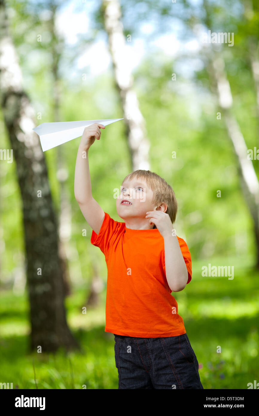 Cute boy holding a paper airplane in park Banque D'Images