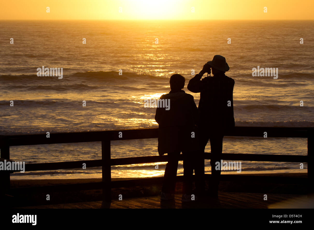 L'homme et la femme regardant le coucher du soleil Banque D'Images