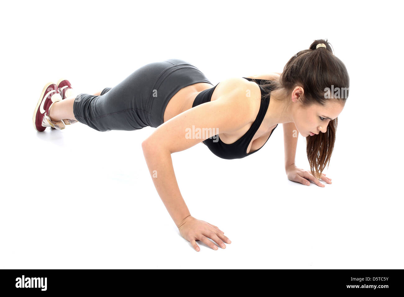 Jeune femme Positive confiant d'effectuer les exercices au sol dans le cadre d'une routine d'entraînement de forme physique isolé sur un fond blanc avec Clipping Path Banque D'Images