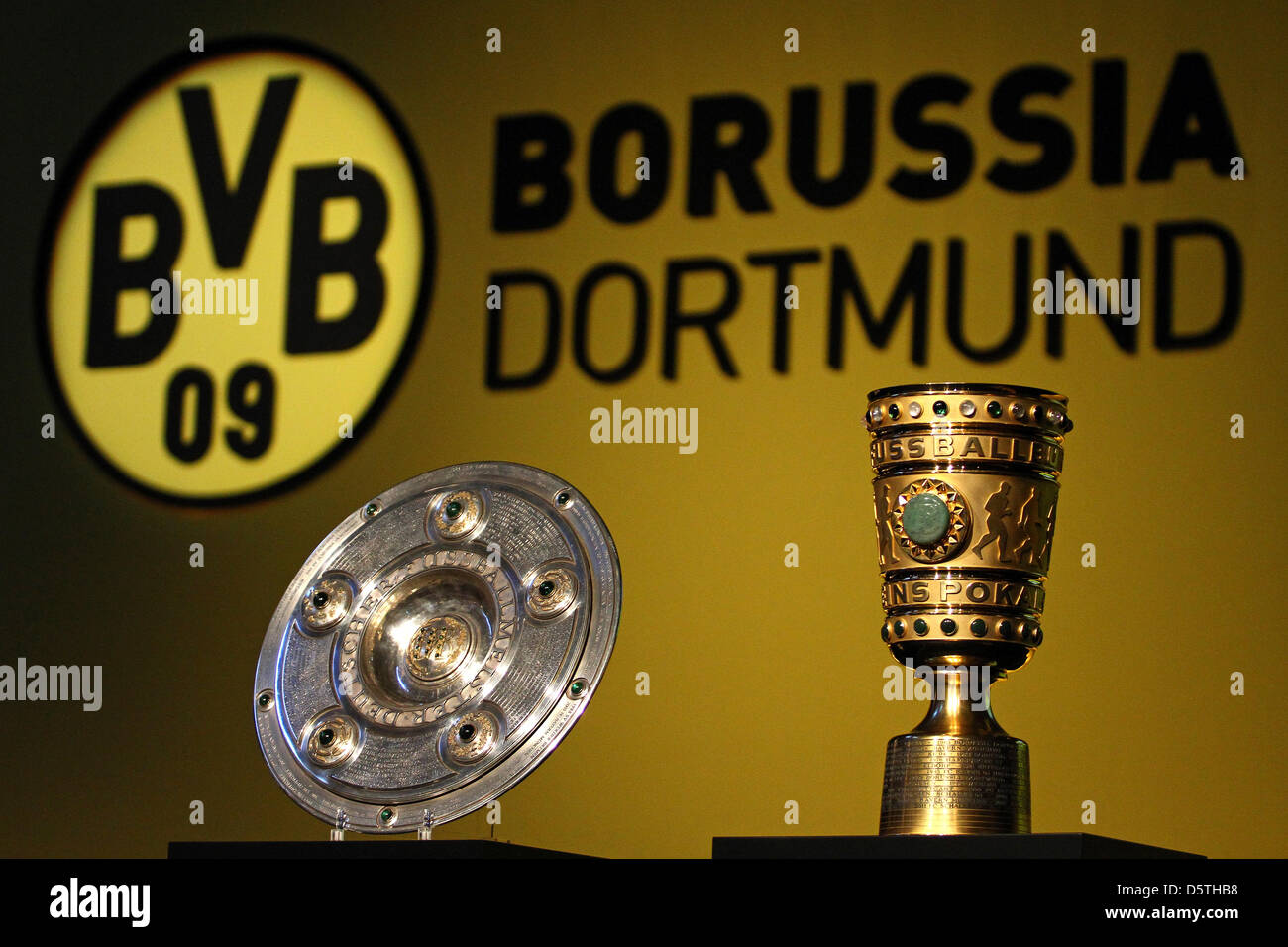 Le trophée du championnat de la Bundesliga et la coupe d'Allemagne sont mis en place en face du club logo du Borussia Dortmund à l'Assemblée générale à la Westfalenhalle à Dortmund, en Allemagne, le 25 novembre 2012. BVB Dortmund a invité ses membres à l'assemblée générale annuelle. Photo : Kevin Kurek Banque D'Images