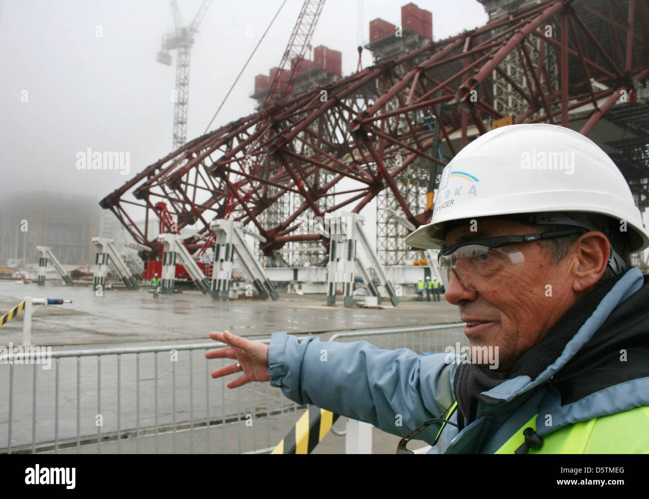 English chef de la sécurité de l'emplacement dans la construction du Tchernobyl, David Jackson, explique le confinement de la construction du nouveau la strcuture pour le réacteur nucléaire (L dans le brouillard) à Tchernobyl, en Ukraine, le 27 novembre 2012. La catastrophe de Tchernobyl a eu lieu en 1986, la nouvelle structure de confinement est prévu d'être mis en place à la fin de 2015. Photo : Wolfgang JUNG Banque D'Images