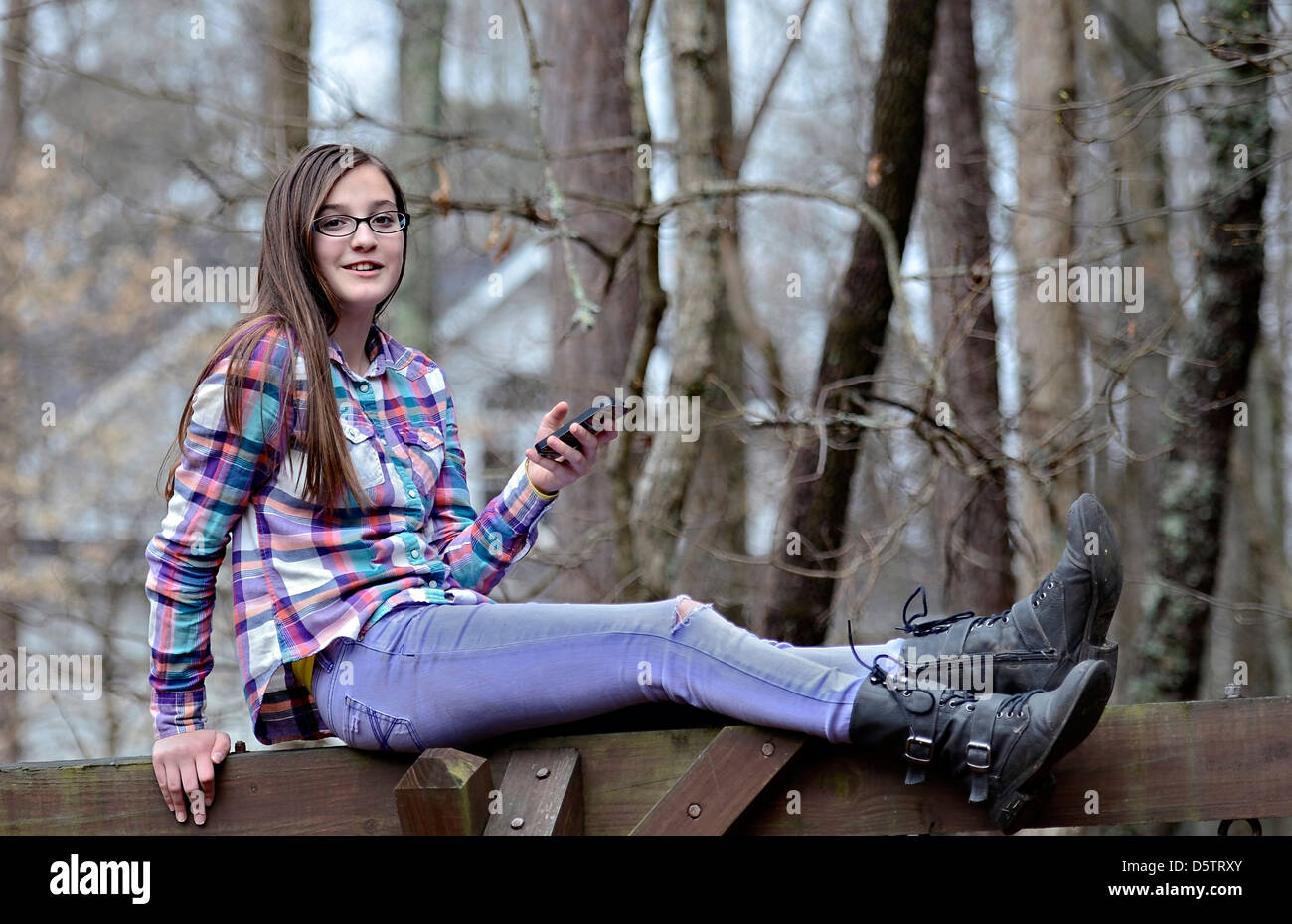 Une belle jeune fille assise à l'extérieur avec son téléphone cellulaire. Banque D'Images