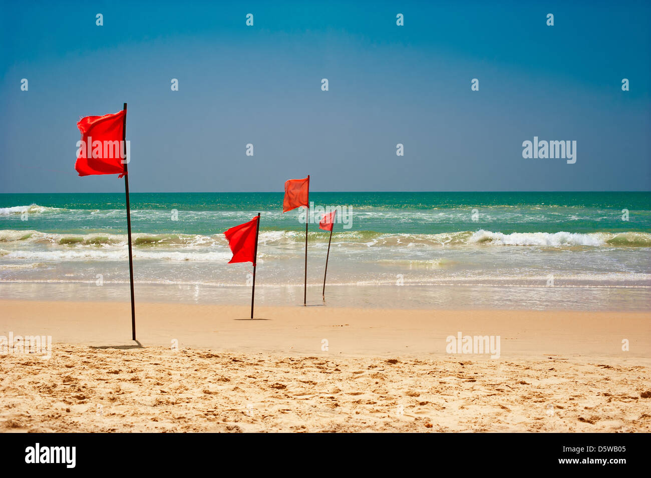 Il est dangereux de nager dans les vagues de l'océan. Drapeau rouge flottant au vent sur la plage au temps orageux Banque D'Images