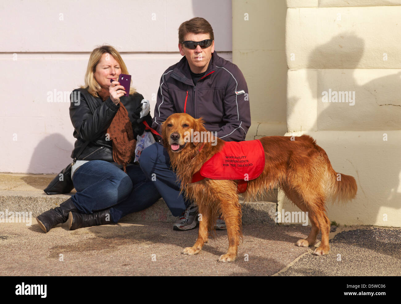 Couple assis avec woofability l'indépendance pour les personnes à mobilité réduite chien Banque D'Images