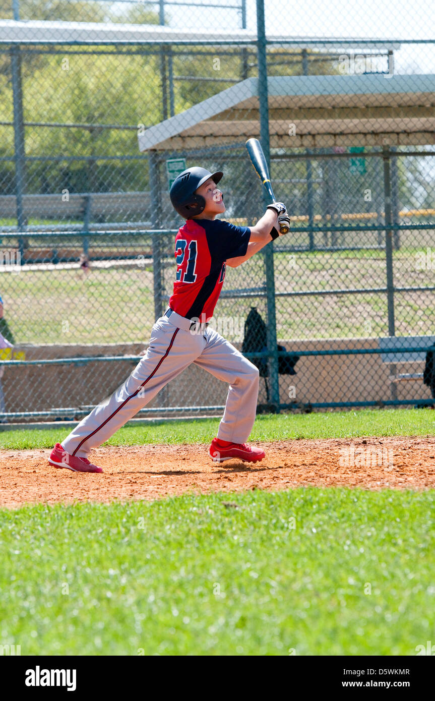 Teen boy baseball player regarder ball après son succès. Banque D'Images