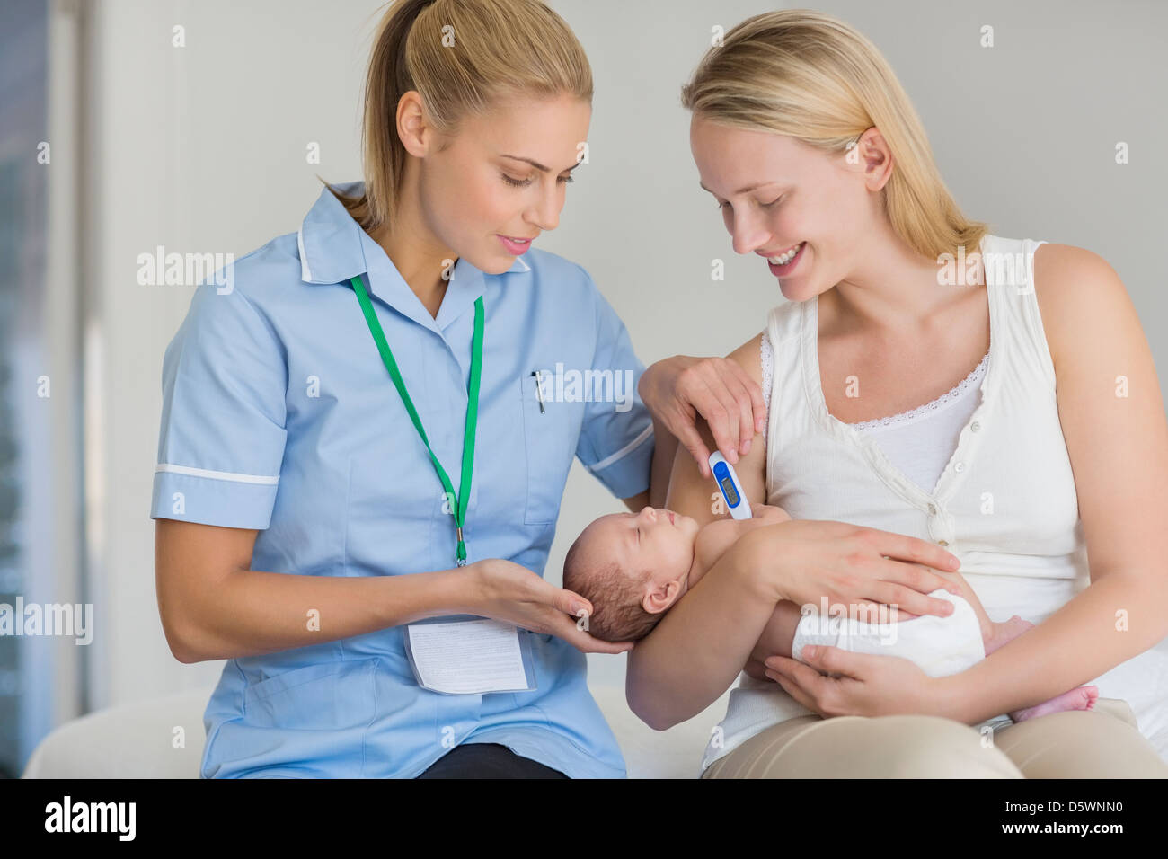 La mère et l'infirmière de prendre la température du bébé nouveau-né Banque D'Images