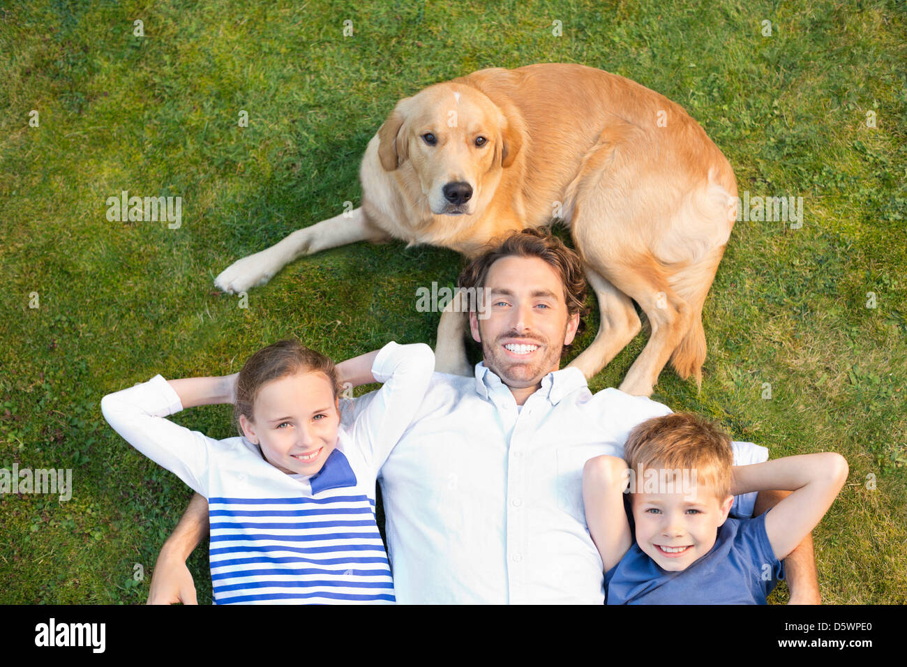 Family relaxing with dog on lawn Banque D'Images