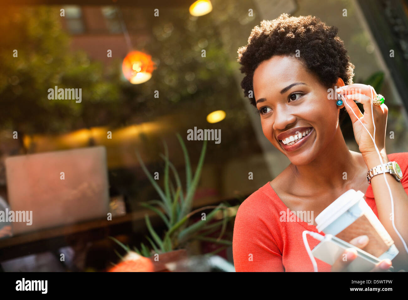 Woman listening to earphones on city street Banque D'Images