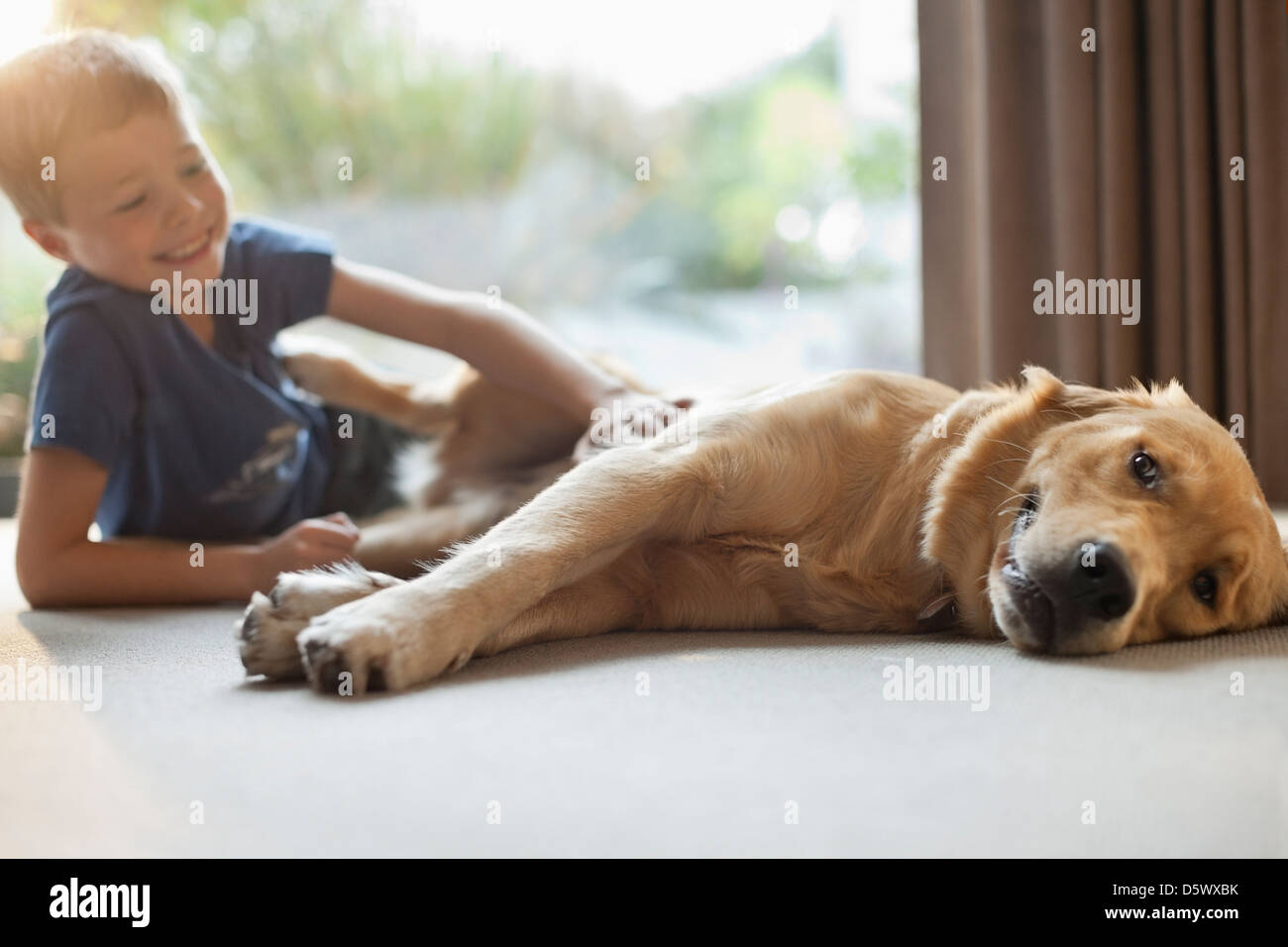 Smiling boy petting dog in living room Banque D'Images