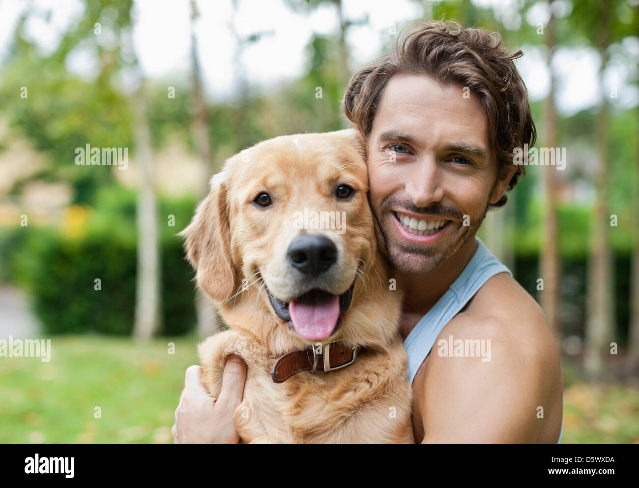 Smiling man petting dog outdoors Banque D'Images