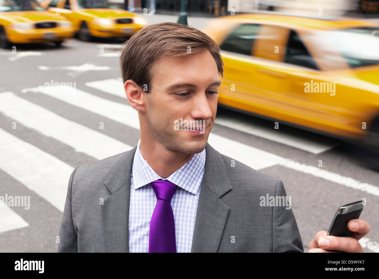 Businessman using cell phone on city street Banque D'Images