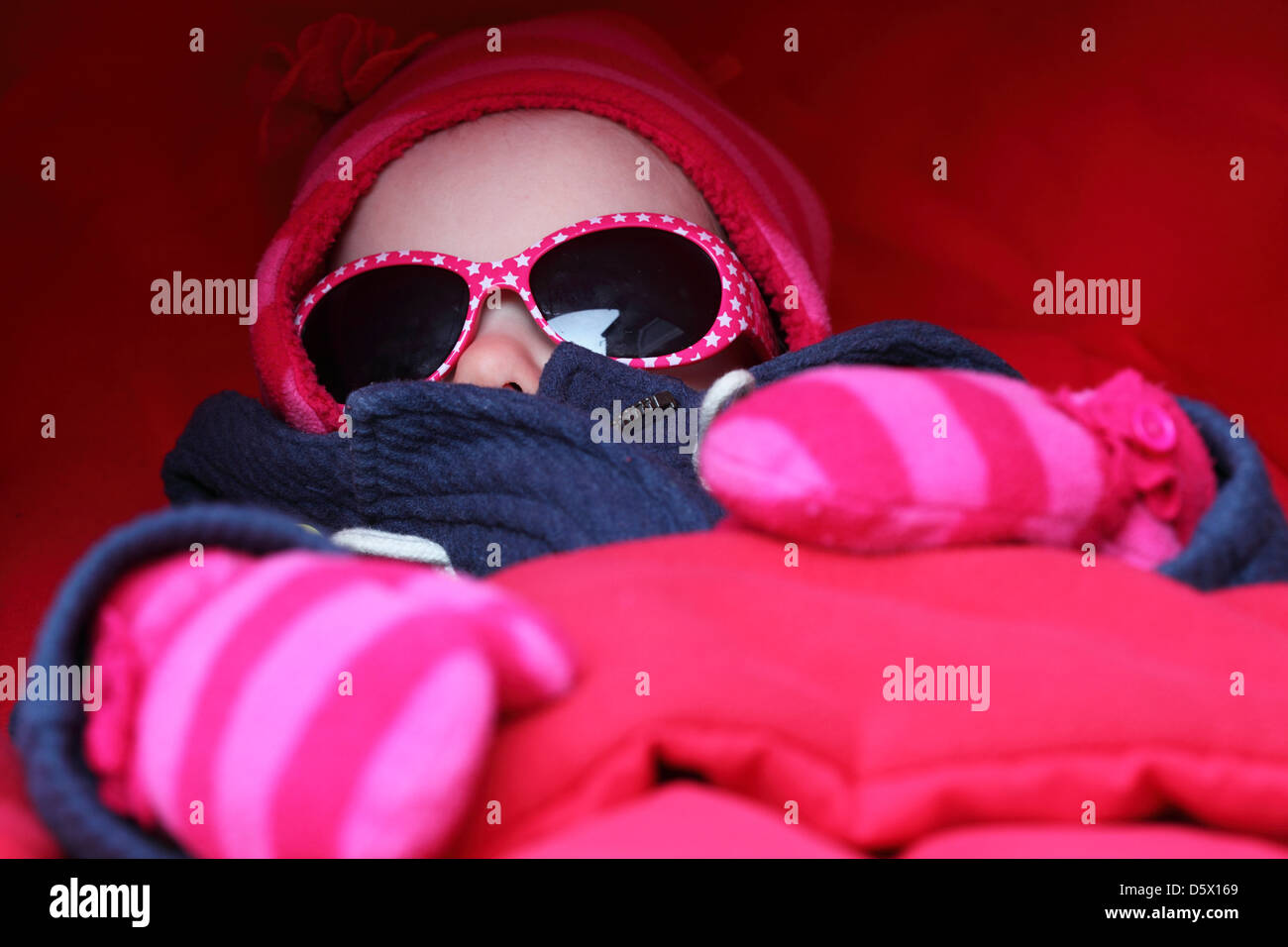 Un bébé endormi porte des nuances, des gants et un chapeau. Banque D'Images