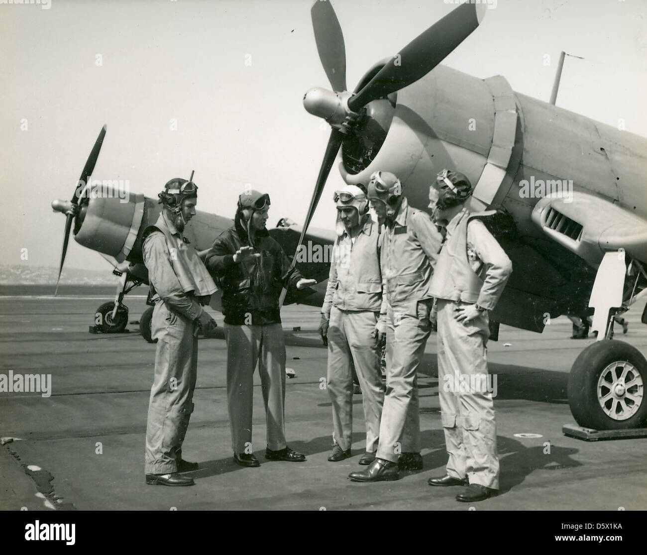 Le lieutenant-commandant Joseph C. Clifton du VF-12 discute d'un vol à bord du Vought F4U Corsair, un chasseur basé sur porte-avions, avec des membres de l'escadron en 1943. Le Corsair a été un avion clé pendant la seconde Guerre mondiale, connu pour son aile courbée distinctive et ses performances supérieures au combat. Banque D'Images