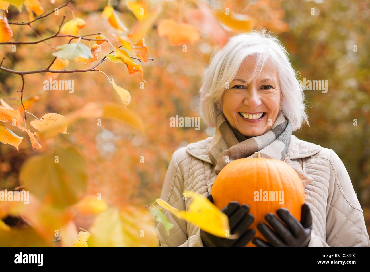 Femme plus âgée holding pumpkin in park Banque D'Images