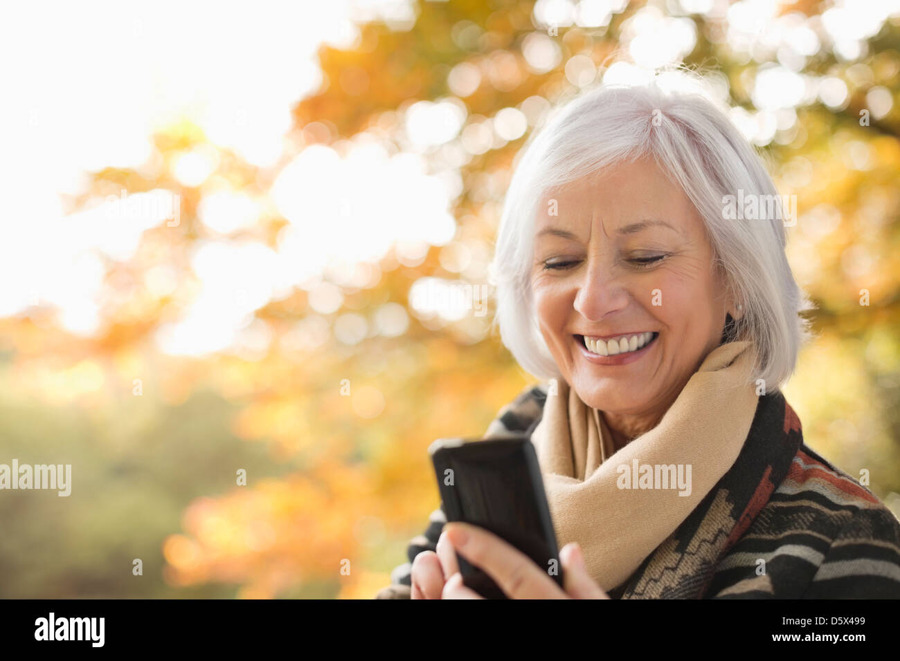 Femme plus âgée using cell phone in park Banque D'Images