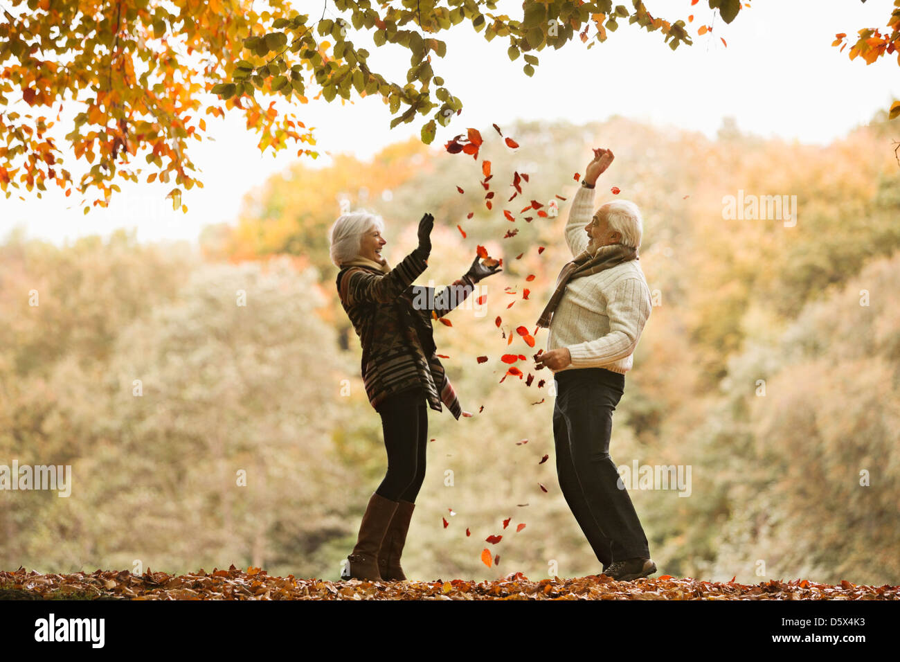 Vieux couple jouant dans les feuilles d'automne Banque D'Images