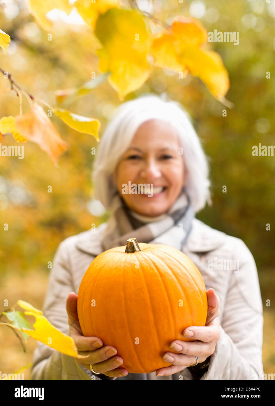Femme plus âgée holding pumpkin in park Banque D'Images