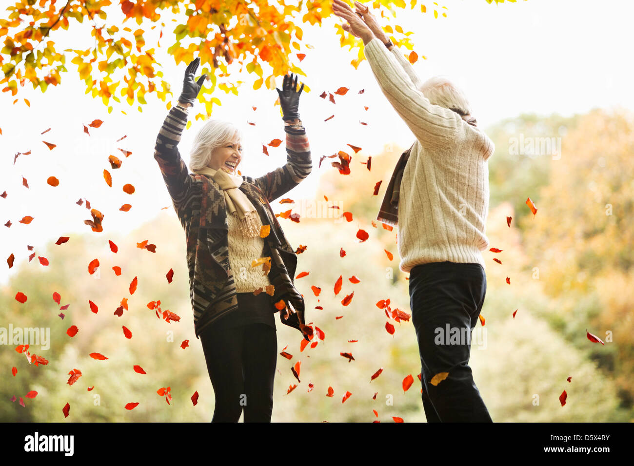 Vieux couple jouant dans les feuilles d'automne Banque D'Images